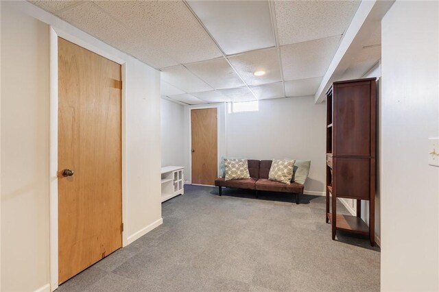 living area featuring carpet floors and a paneled ceiling