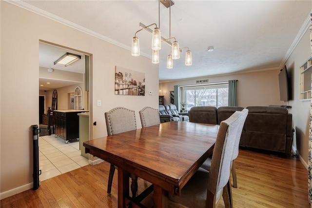 dining room with light hardwood / wood-style flooring and crown molding