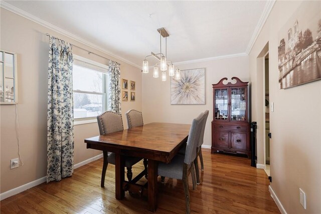 dining room featuring hardwood / wood-style flooring, ornamental molding, and a notable chandelier