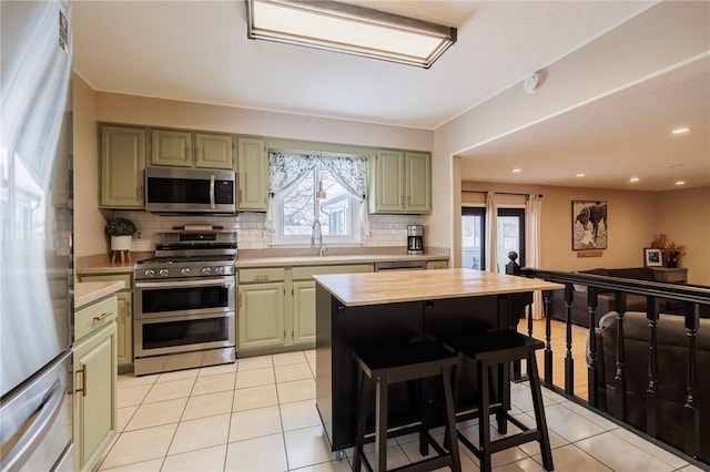 kitchen with a kitchen breakfast bar, light tile patterned floors, stainless steel appliances, and green cabinetry