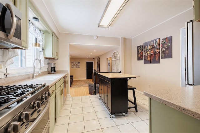 kitchen featuring sink, light tile patterned floors, refrigerator, a kitchen island, and a breakfast bar area