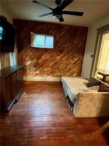 unfurnished bedroom with ceiling fan, dark wood-type flooring, and wooden walls