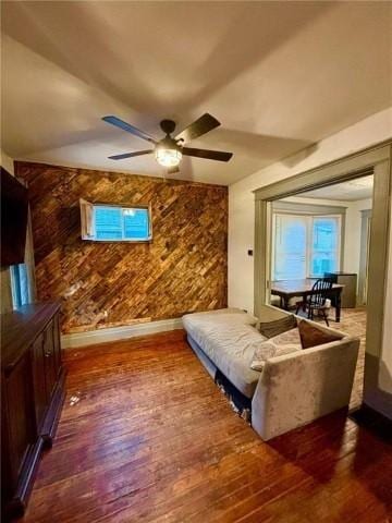 interior space with ceiling fan, dark wood-type flooring, and wooden walls