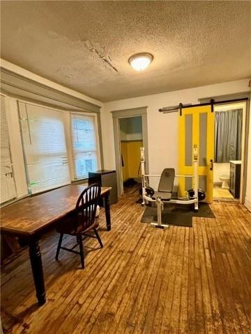 workout room featuring wood-type flooring, a textured ceiling, and a barn door