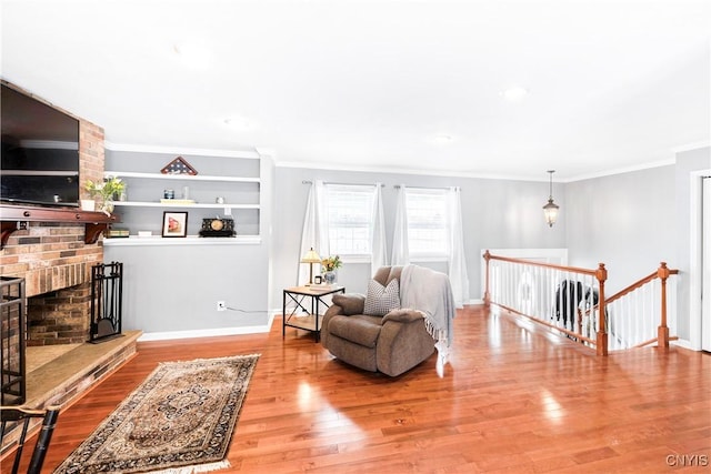 sitting room featuring built in features, crown molding, and hardwood / wood-style floors