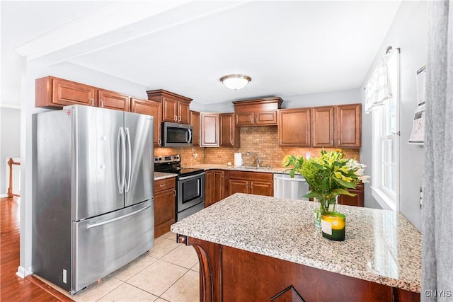 kitchen featuring light stone countertops, appliances with stainless steel finishes, tasteful backsplash, light tile patterned floors, and sink