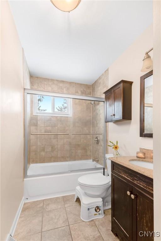 full bathroom featuring combined bath / shower with glass door, vanity, toilet, and tile patterned flooring