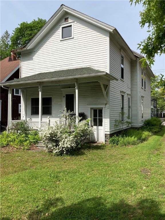 rear view of property with covered porch and a lawn