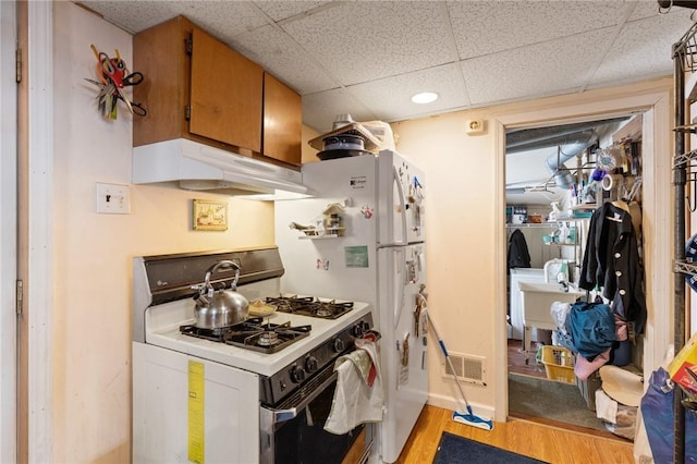 kitchen featuring a drop ceiling, white gas range, and light wood-type flooring