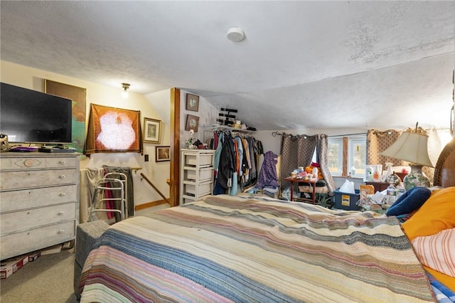 bedroom with carpet, a textured ceiling, and lofted ceiling