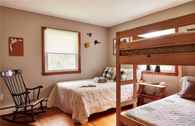 bedroom with baseboard heating, multiple windows, and hardwood / wood-style floors