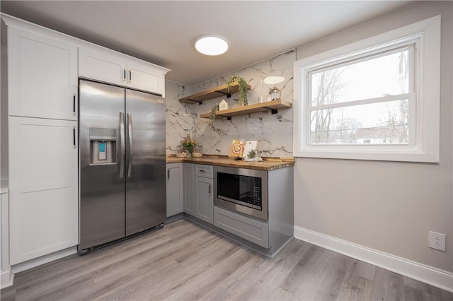 kitchen featuring butcher block counters, white cabinetry, gray cabinetry, stainless steel appliances, and light hardwood / wood-style floors