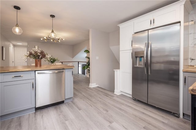 kitchen featuring stainless steel appliances, white cabinetry, and wooden counters