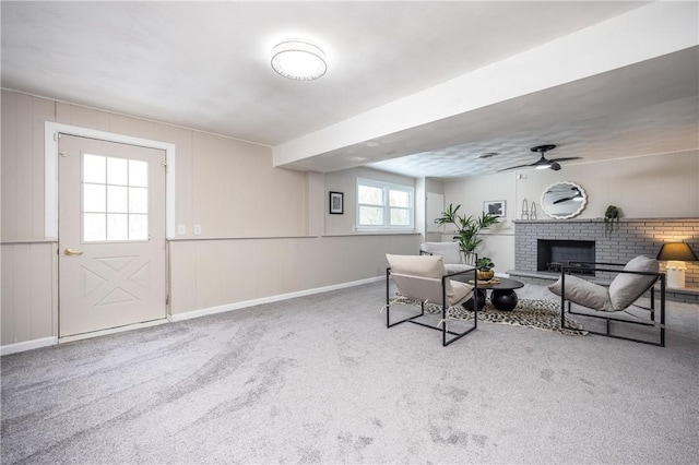 living room with a brick fireplace, carpet, and ceiling fan