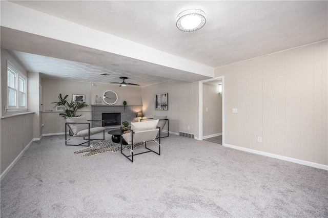 carpeted living room with a brick fireplace and ceiling fan