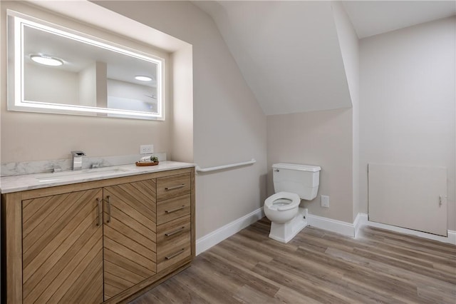 bathroom with vanity, hardwood / wood-style floors, vaulted ceiling, and toilet