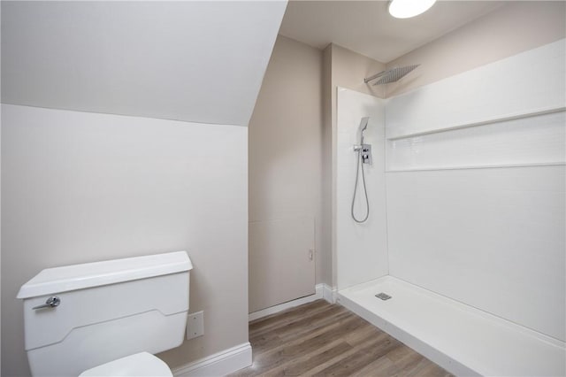 bathroom with hardwood / wood-style flooring, vaulted ceiling, toilet, and a shower