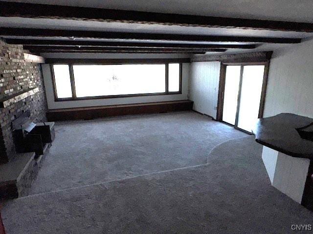 unfurnished living room featuring carpet and beam ceiling