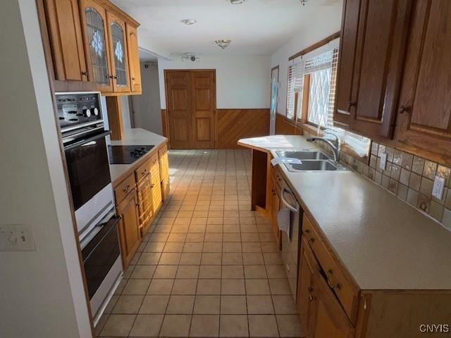 kitchen featuring sink, wooden walls, wall oven, and black electric cooktop