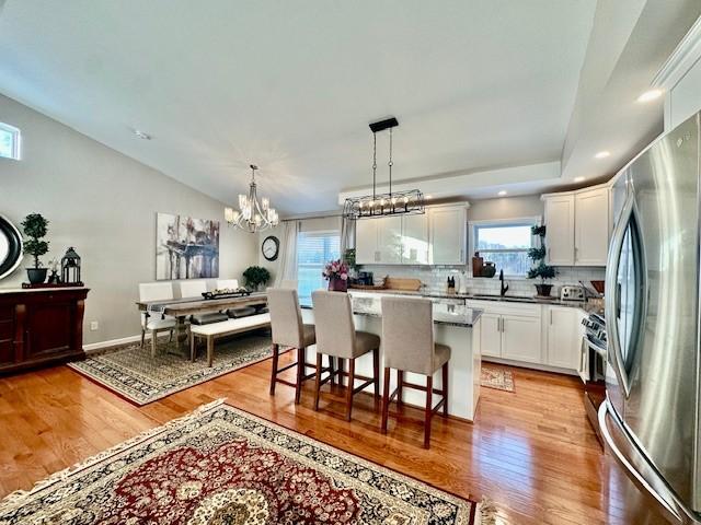 kitchen with decorative light fixtures, white cabinetry, a kitchen island, decorative backsplash, and stainless steel appliances