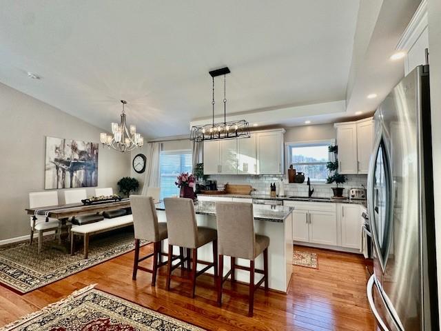 kitchen featuring a center island, white cabinetry, sink, hanging light fixtures, and stainless steel fridge