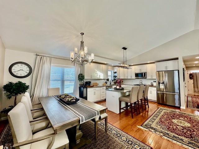 dining room featuring hardwood / wood-style flooring, a chandelier, and lofted ceiling