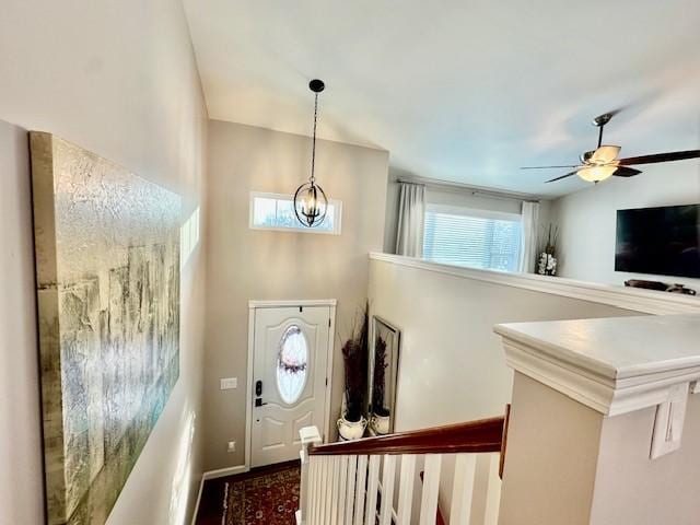 entryway featuring ceiling fan with notable chandelier