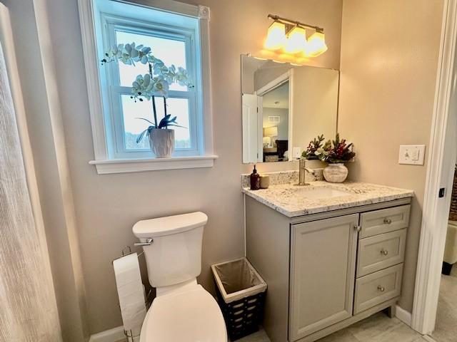 bathroom featuring a wealth of natural light, toilet, and vanity