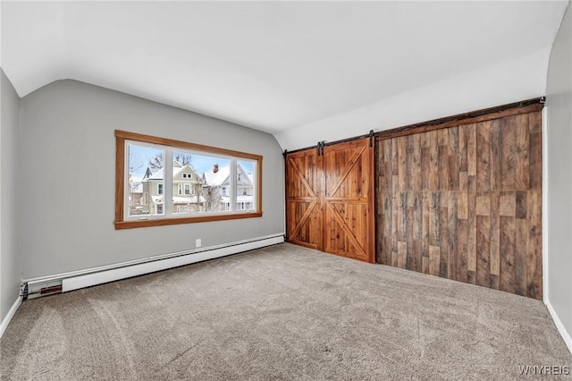 carpeted spare room with baseboard heating, lofted ceiling, and a barn door