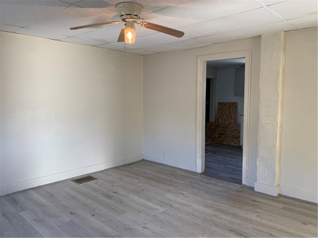 empty room with light wood-type flooring, ceiling fan, and a paneled ceiling