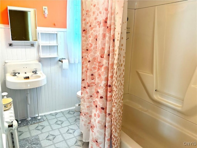 bathroom with sink, wood walls, and shower / bath combo with shower curtain