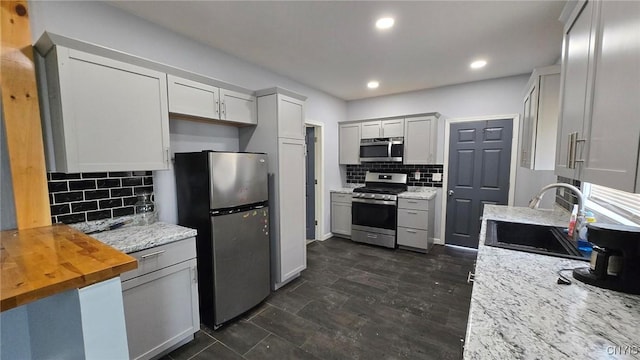 kitchen featuring tasteful backsplash, sink, stainless steel appliances, and wooden counters