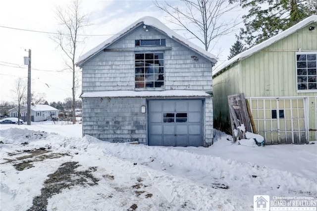 snow covered structure featuring a garage