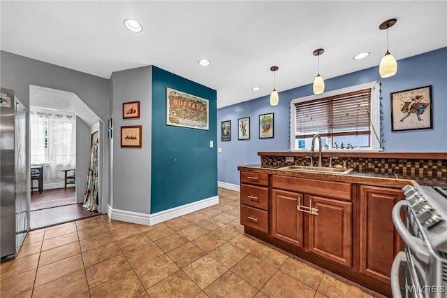 kitchen featuring light tile patterned flooring, appliances with stainless steel finishes, pendant lighting, a wealth of natural light, and sink