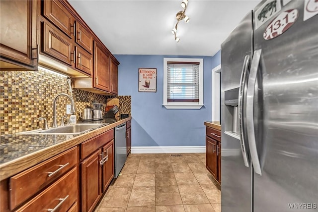 kitchen with stainless steel appliances, light tile patterned flooring, sink, and decorative backsplash