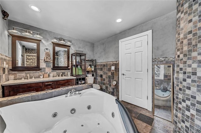 bathroom featuring vanity, a bath, and tile walls