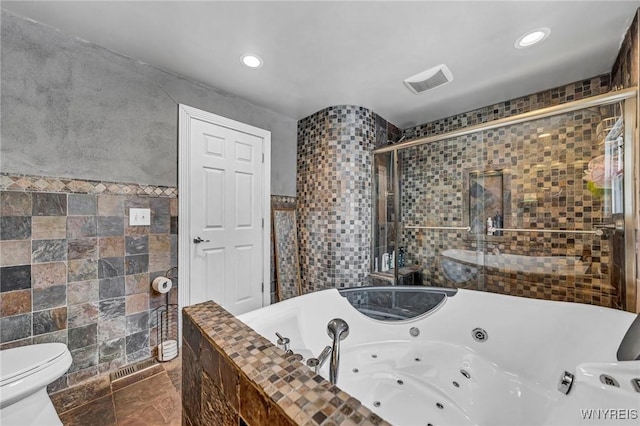 bathroom featuring toilet, independent shower and bath, and tile walls