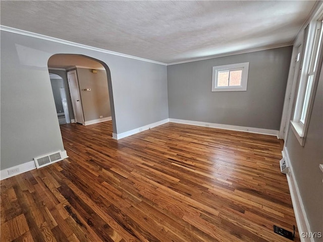 empty room with dark wood-type flooring, ornamental molding, and a textured ceiling