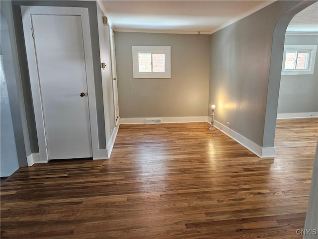 spare room featuring a healthy amount of sunlight, ornamental molding, and dark hardwood / wood-style floors