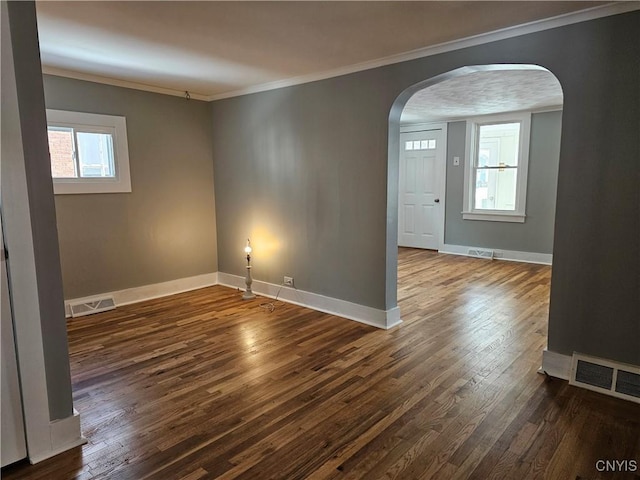 spare room with a healthy amount of sunlight, dark wood-type flooring, and crown molding