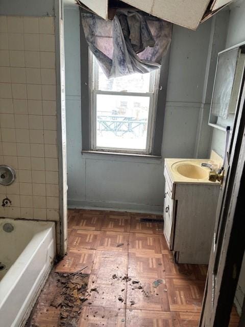 bathroom featuring parquet flooring, vanity, and tiled shower / bath combo