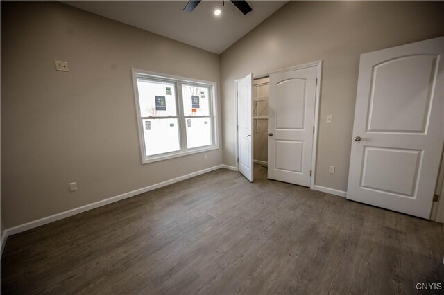 unfurnished bedroom featuring lofted ceiling, dark hardwood / wood-style floors, and ceiling fan