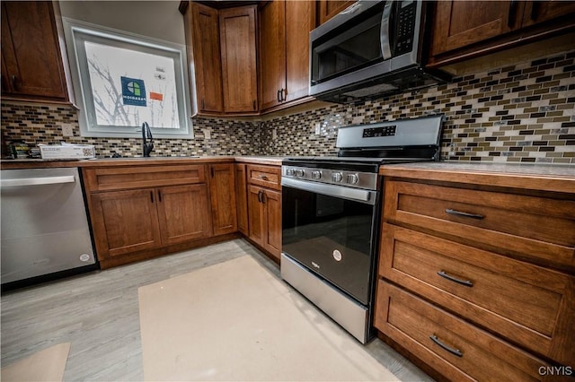 kitchen featuring appliances with stainless steel finishes, sink, backsplash, and light hardwood / wood-style floors