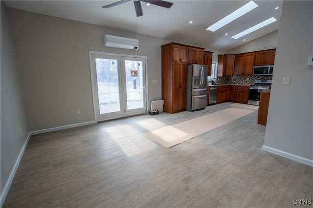 kitchen with tasteful backsplash, a wall mounted air conditioner, light hardwood / wood-style flooring, stainless steel appliances, and vaulted ceiling with skylight