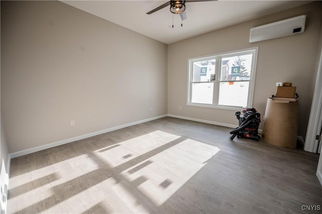 spare room featuring ceiling fan, a wall mounted air conditioner, and light wood-type flooring