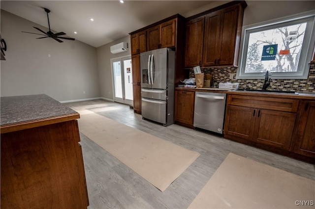 kitchen featuring lofted ceiling, sink, a wall mounted air conditioner, light wood-type flooring, and stainless steel appliances