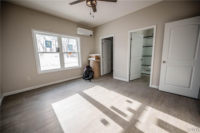 unfurnished bedroom featuring ensuite bathroom, light wood-type flooring, a wall mounted AC, and ceiling fan