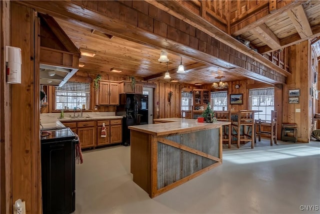 kitchen with tile countertops, wood walls, sink, hanging light fixtures, and black appliances