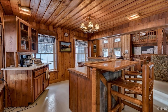 kitchen featuring a notable chandelier, wood ceiling, wooden walls, and kitchen peninsula