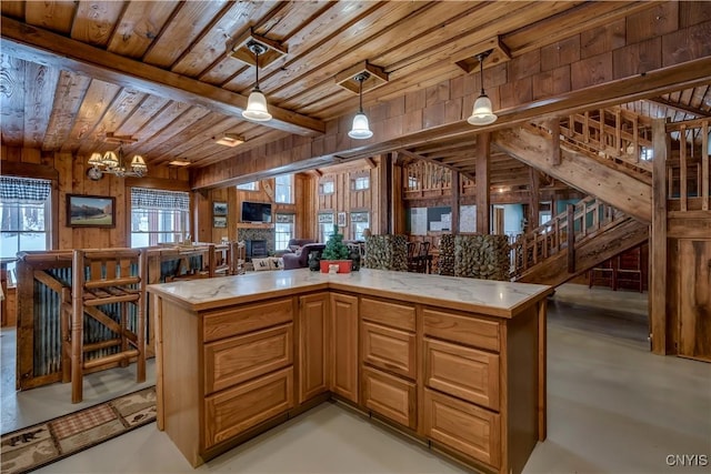 kitchen with pendant lighting, wood ceiling, wooden walls, a notable chandelier, and a fireplace